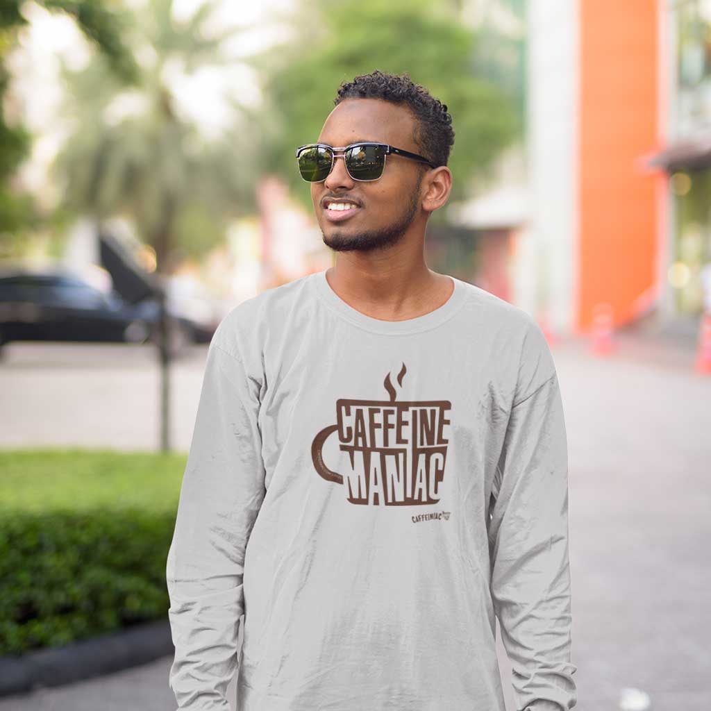 a smiling man in sunglasses wearing a light grey long sleeve tshirt by Caffeiniac featuring the design CAFFEINE MANIAC