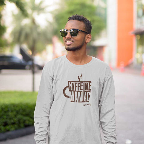 Image of a smiling man in sunglasses wearing a light grey long sleeve tshirt by Caffeiniac featuring the design CAFFEINE MANIAC