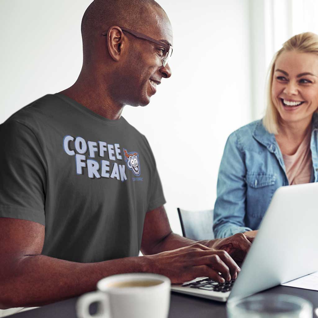 man at laptop computer wearing a grey Caffeiniac t-shirt with the COFFEE FREAK design on the front