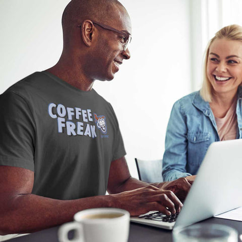 Image of man at laptop computer wearing a grey Caffeiniac t-shirt with the COFFEE FREAK design on the front