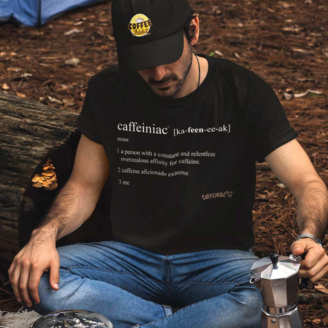 Image of a man camping in the woods with a pot of coffee wearing a black tshirt