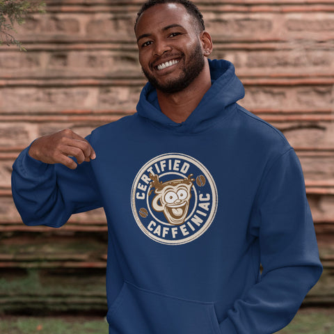 Image of Man standing outdoors wearing a navy blue unisex hoodie with the Certified Caffeiniac design on front in tan ink
