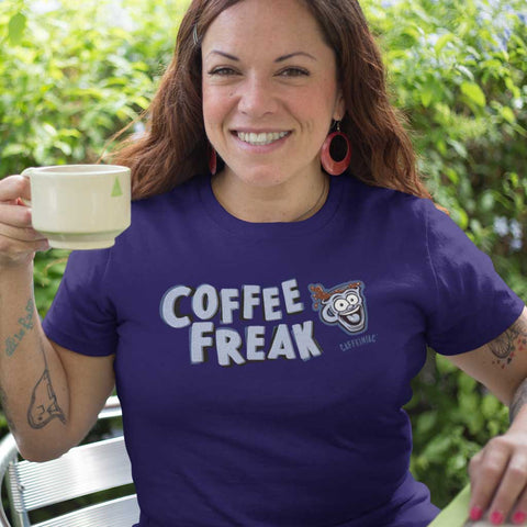 Image of smiling woman on a patio holding a cup of coffee wearing the Caffeiniac COFFEE FREAK t-shirt