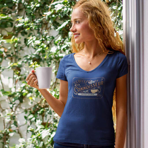Image of a woman on a patio wearing a navy blue v-neck shirt with the coffee connoisseur design by caffeiniac