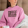 pink hoodie featuring the COFEE OBSESSED design on the front