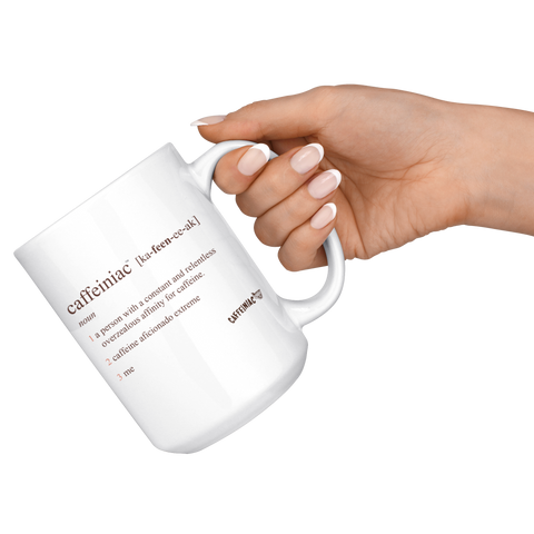 Image of a womans hand with a French manicure holding a white coffee mug with the original Caffeiniac defined design in brown ink