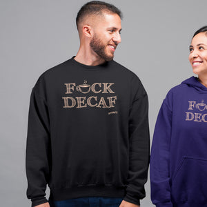smiling man standing wearing a black crewneck sweatshirt with the original Caffeiniac design F_CK DECAF on the front in tan ink