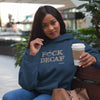 woman on a bench wearing a navy blue hoodies sweatshirt holding a cup of coffee. The front of the sweatshirt features the Cafffeiniac design F_CK DECAF