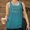 woman at a coffee shop holding a cup of coffee wearing a teal tank top with the original Caffeiniac design F_CK DECAF on the front in tan ink