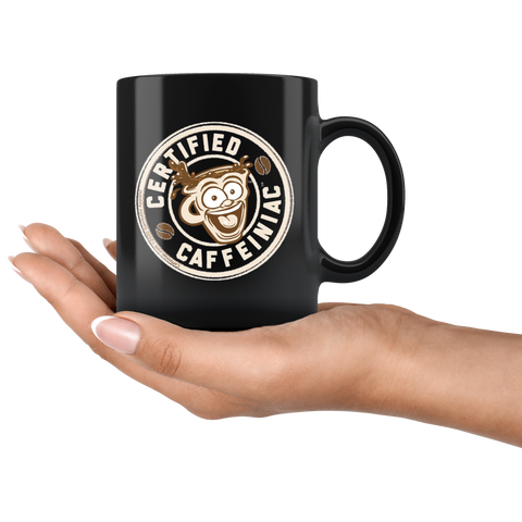 Image of a black coffee mug featuring the Certified Caffeiniac design in tan and brown printed on the front and back resting on a woman's palm