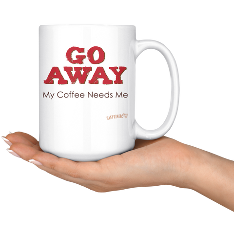 Image of white ceramic coffee mug with the Caffeiniac design GO AWAY My Coffee Needs Me on both sides resting on the palm of a woman's hand