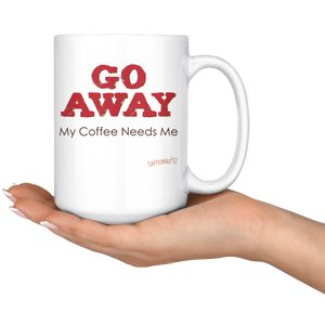 white ceramic coffee mug with the Caffeiniac design GO AWAY My Coffee Needs Me on both sides resting on the palm of a woman's hand