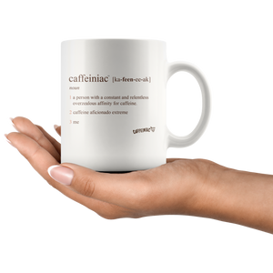 a woman holding a white 11oz coffee mug with the original Caffeiniac defined design in brown ink