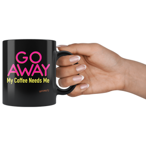 a woman's hand holding a black coffee mug featuring the Caffeiniac design "GO AWAY My Coffee Needs Me" in vibrant color on front and back.
