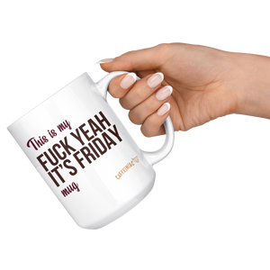 a hand holding the handle of a white ceramic mug that says This is my fuck yeah it's friday mug