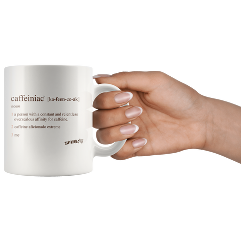 Image of Front view of a white 11oz coffee mug by the handle  with the original Caffeiniac defined design in brown ink
