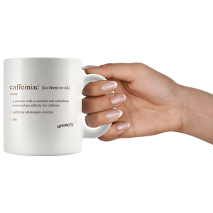 Front view of a white 11oz coffee mug by the handle  with the original Caffeiniac defined design in brown ink